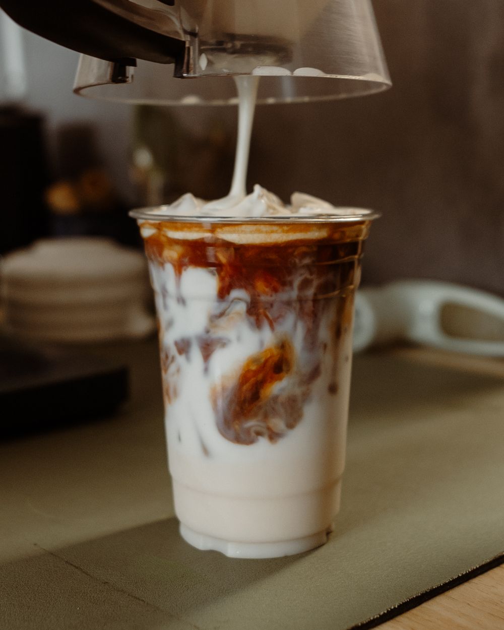 Milk pouring into an iced latte with a caramel swirl