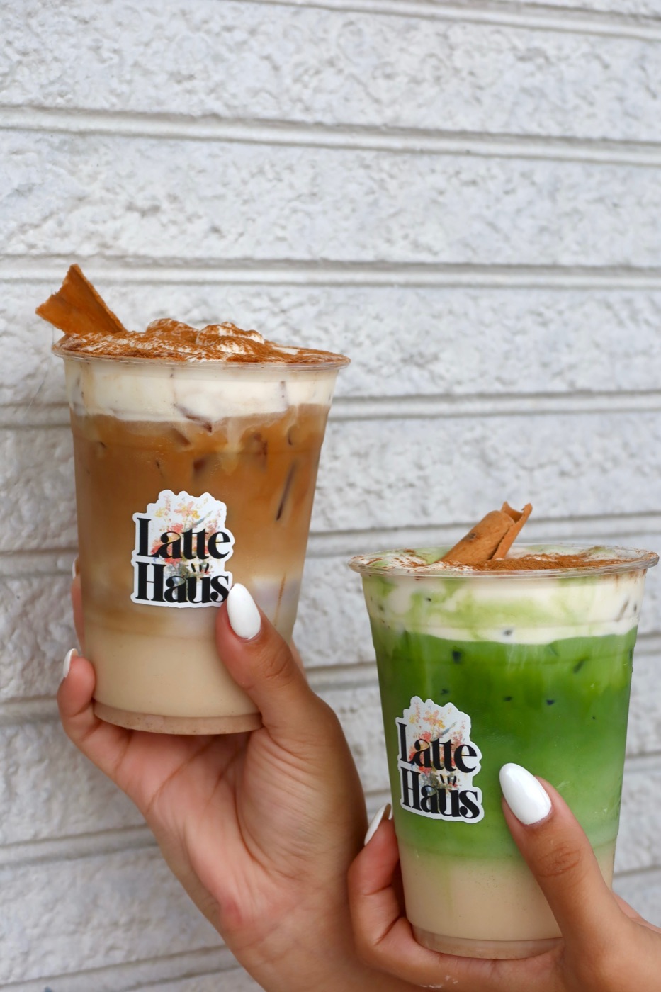 Horchata Latte and matcha Horchata Latte held against white brick at Latte Haus