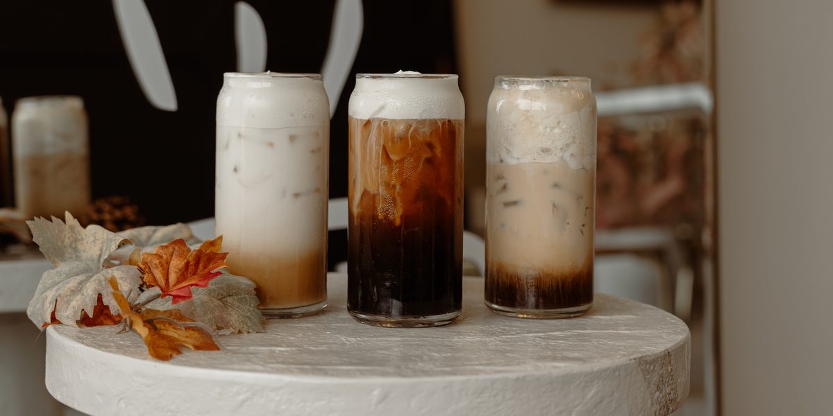 Calabaza Latte, Pumpkin Pie Cold Brew and Calabaza Chai lined up on a white pedestal with fall leaves